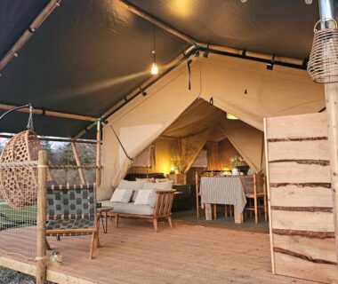 Terrasse en bois avec salon et table dans la tente du camping Le Ranch Camping et Glamping