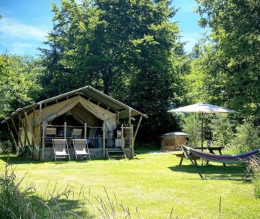 Pelouse avec tente glamping chaises hamac et spa extérieur au camping Le Ranch Camping et Glamping