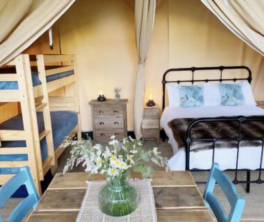 Intérieur de tente avec lit double et lits superposés dans le camping Le Ranch Camping et Glamping