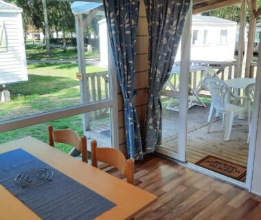 Intérieur de mobil-home avec table et terrasse dans Le Ried Camping To hapi
