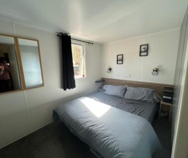 Chambre double avec lit, fenêtre et rangements au camping Le SaraLéna