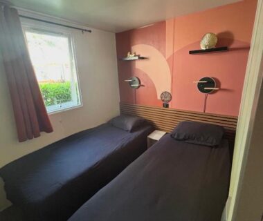 Chambre avec deux lits simples et mur rose au camping Le SaraLéna