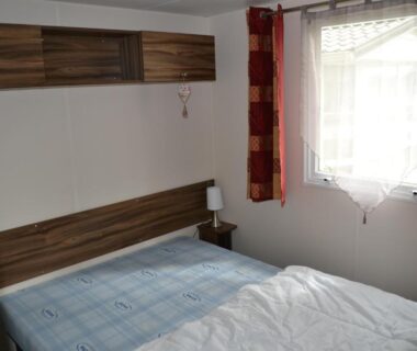 Chambre avec lit double, fenêtre et rangements dans le mobil-home Le Sherwood