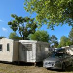 Allée ombragée avec mobil-homes et voiture garée dans le camping Le Sherwood - Mobil-Home