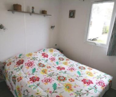 Intérieur chambre avec lit double et fenêtre dans le mobil-home Le balaou