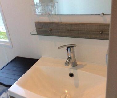 Salle de bain avec lavabo, robinet et miroir du camping Le balaou