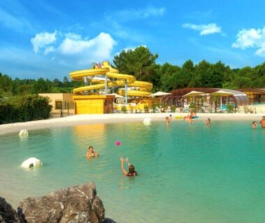 Lagon de piscine avec toboggans jaunes et plage au camping Le balaou