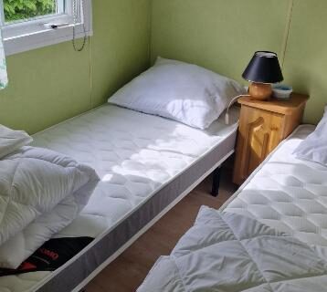 Chambre avec deux lits simples et lampe dans le mobilhome Le beau mobilhome