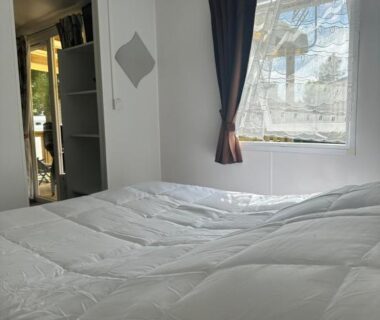 Chambre avec lit et fenêtre dans le mobil-home du camping Le bercail
