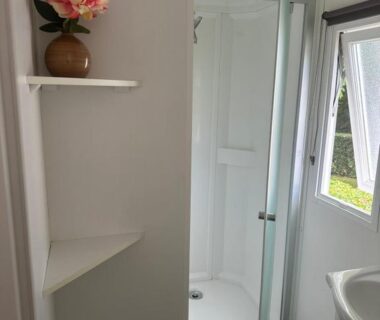 Salle d'eau avec cabine de douche vitrée et lavabo dans Le bercail