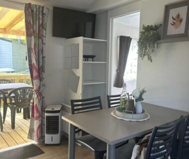 Intérieur avec coin repas et terrasse donnant sur une terrasse extérieure au camping Le bercail