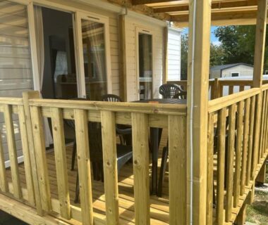 Terrasse en bois avec rambarde et porte vitrée du mobil-home Le bercail