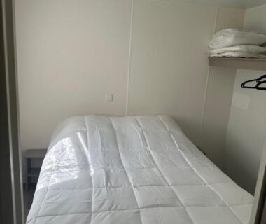 Chambre avec lit double et étagère dans le camping Le bercail