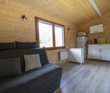 Intérieur en bois avec kitchenette et canapé du chalet de DOMY