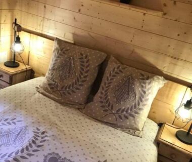 Chambre avec lit en bois coussins et lampes dans Le chalet de DOMY