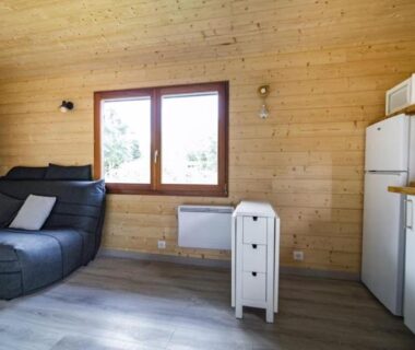 Intérieur de chalet avec canapé et kitchenette du chalet Le chalet de DOMY