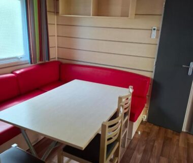 Coin repas avec banquette rouge et table dans le mobil-home Le nid Rhénan