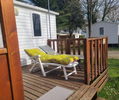 Terrasse en bois avec transat et coussin jaune du camping Le petit home d'audrey