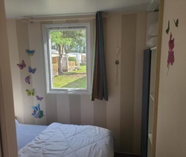 Chambre avec lit et fenêtre sur le camping dans Le petit home d'audrey