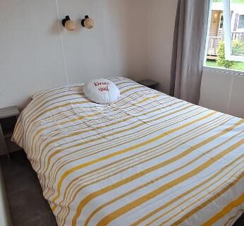 Chambre avec lit double et fenêtre dans Le petit mobilhome de Charlotte à Saint Georges de Didonne