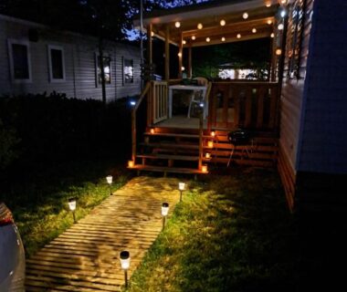 Allée éclairée et terrasse de mobil-home la nuit au camping L'échapée verte