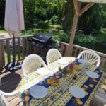 Terrasse en bois avec table chaises et barbecue au camping L'échappée verte au bord de l'Eure