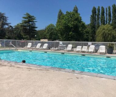 Piscine extérieure bordée de transats au camping L'échappée verte au bord de l'Eure