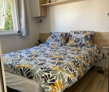 Dans le mobil-home chambre avec grand lit et fenêtre au camping L'écureuil