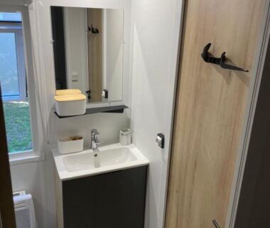 Salle d'eau avec lavabo miroir et fenêtre du camping L'écureuil
