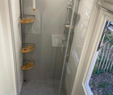 Salle d'eau avec cabine de douche et étagères près de la fenêtre au camping L'écureuil