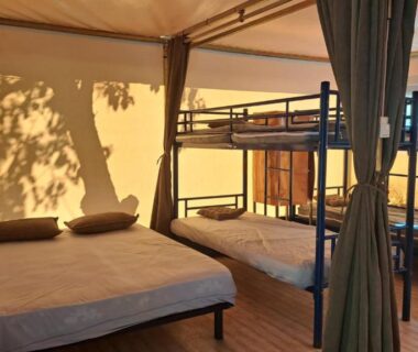 Intérieur de tente avec lit double et lits superposés dans Les 2 étangs La Foulonnerie Lodge Tente