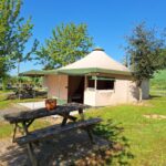Table de pique-nique devant une tente sur la pelouse au camping Les 2 étangs La Foulonnerie Lodge - Tente
