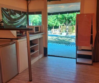 Intérieur de tente avec kitchenette et vue sur la piscine au camping Les 2 étangs La Foulonnerie Lodge Tente