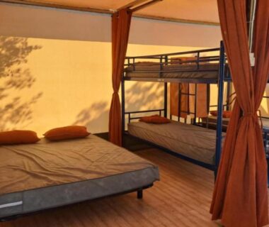 Intérieur de tente avec lit double et lits superposés dans la Tente Les 2 étangs La Foulonnerie Lodge