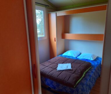 Intérieur chambre avec lit double et fenêtre dans le mobil-home Les 5 Étangs
