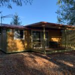 Dans un espace boisé chalet en bois avec terrasse couverte au camping Les 5 Étangs