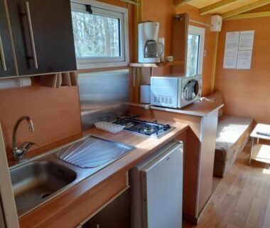 Intérieur kitchenette avec évier plaques et coin repas du mobil-home Les 5 Étangs