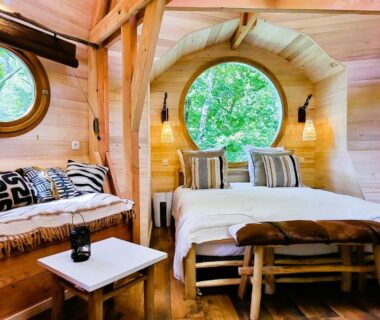 Intérieur de cabane en bois avec lit et hublots au camping Les 7 Montagnes