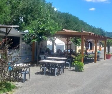 Allée et terrasses avec tables et pergolas au camping Les Berges Du Cele