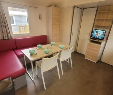 Intérieur de mobil-home avec coin repas et banquette au camping Les Berges Du Cele