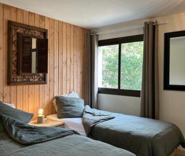 Chambre avec deux lits et fenêtre sur la végétation aux Chalets de Labeaume