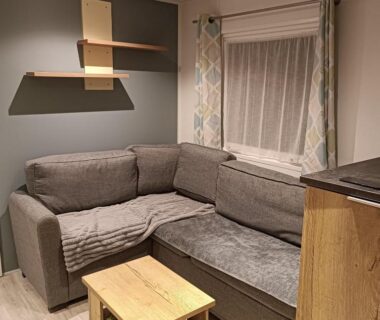 Salon avec canapé d'angle gris et table basse du mobil-home Les Ch'tis Normands 2