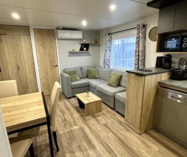 Séjour avec canapé et kitchenette dans le mobil-home Les Dunes d'EZC