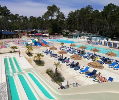 Espace aquatique avec toboggans transats et parasols au camping Les Dunes de Contis