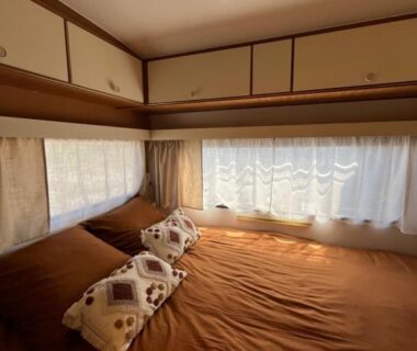 Chambre avec lit double coussins et rangements dans le mobil-home Les Hulottes