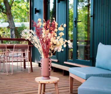 Terrasse en bois avec canapé et vase de fleurs au camping Les Maritimes