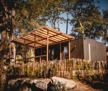 Bungalow en bois sur terrasse sous les arbres au camping Les Maritimes