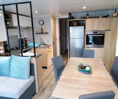 Séjour avec cuisine équipée table et canapé dans le mobil-home Les Pins del Sol du camping la réserve