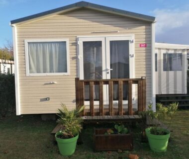 Mobil-home avec petite terrasse en bois et pots de fleurs au camping Les Pins del Sol