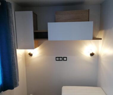 Intérieur chambre avec lit appliques et rangements dans le camping Les Pins del Sol camping la réserve